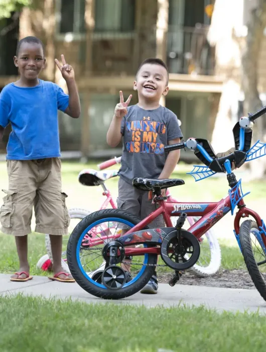Aeon Affordable Homes with two young boys playing outside an apartment building with a bike